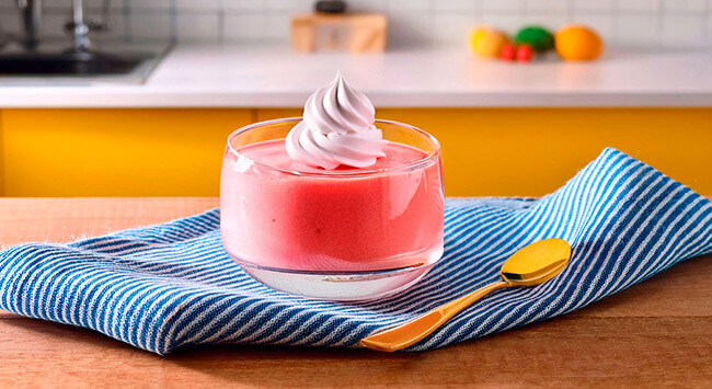 Mousse de morango servido em uma pequena tigela transparente.