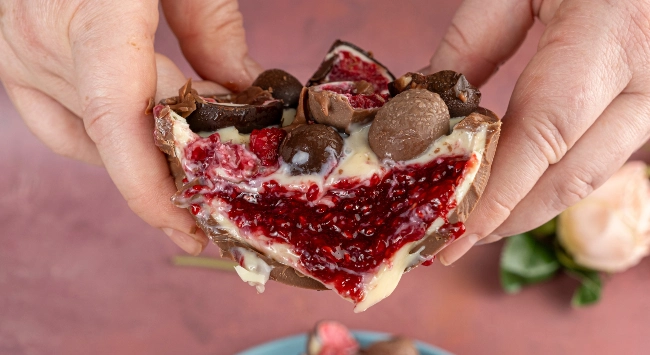 Ovo caseiro cortado ao meio para evidenciar o recheio cremoso de framboesa e chocolate branco.