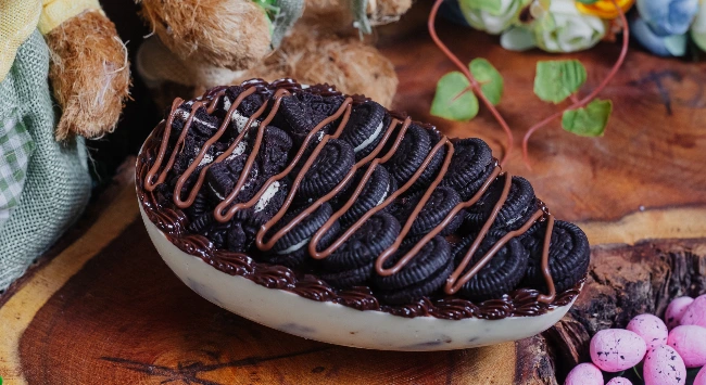Ovo de chocolate branco recheado com creme de avelã e decorado com biscoitos.