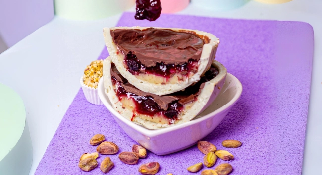 Delicioso ovo cortado ao meio e recheado com pistache e frutas vermelhas.